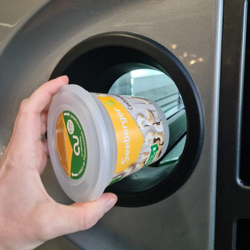 Mehrweg-Verpackungslösungen auf einem Tisch, bestehend aus wiederverwendbaren Behältern und Beuteln in verschiedenen Größen und Materialien.