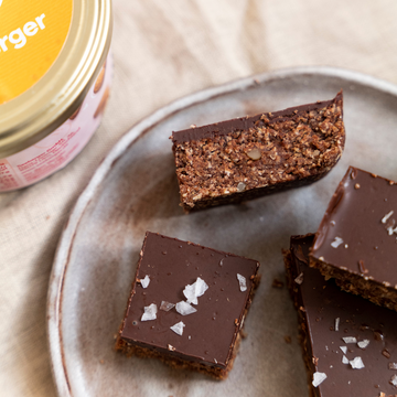 Schokoladenriegel liegen auf einem Teller, daneben ein Behälter auf einem Tuch.